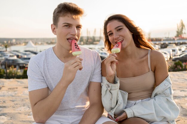 Beau couple mangeant des sucettes glacées à l'extérieur