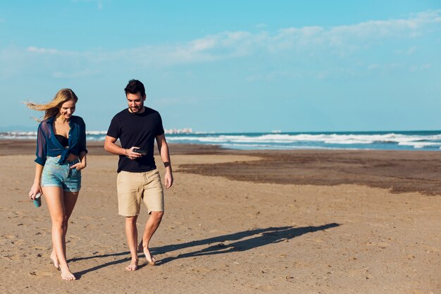 Beau couple marchant sur la plage de sable