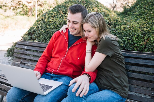 Beau couple, navigation sur ordinateur portable sur le banc