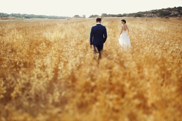 Beau couple en promenade romantique en cours d&#39;exécution et en souriant dans le champ d&#39;été.