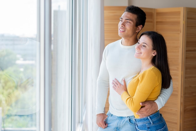 Beau couple regardant par la fenêtre