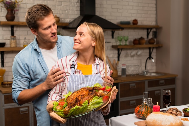 Beau couple se regardant et tenant la dinde de Thanksgiving