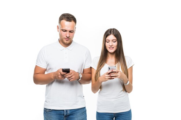 Beau couple avec des téléphones mobiles à la recherche de quelque chose de studio photo sur blanc