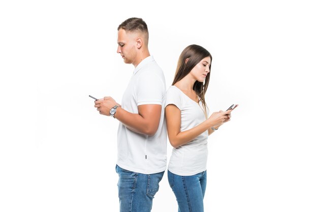 Beau couple avec des téléphones mobiles restant l'un à l'autre isolé sur blanc