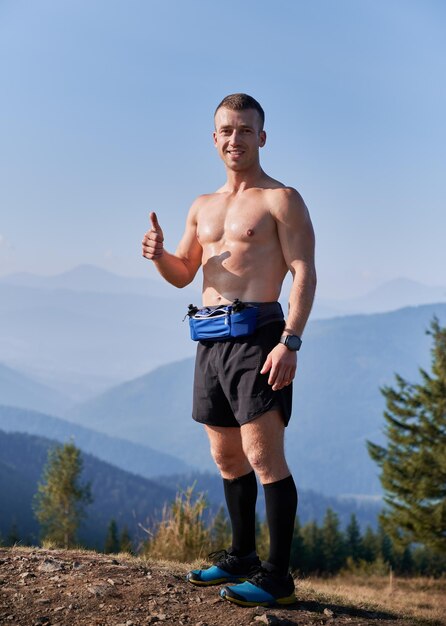 Beau coureur sportif debout au sommet d'une colline de montagne