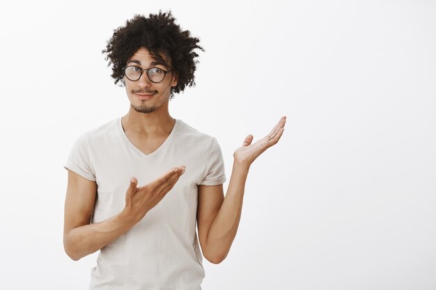 Beau développeur masculin dans des verres, homme pointant le coin supérieur droit avec un sourire heureux, présenter le produit