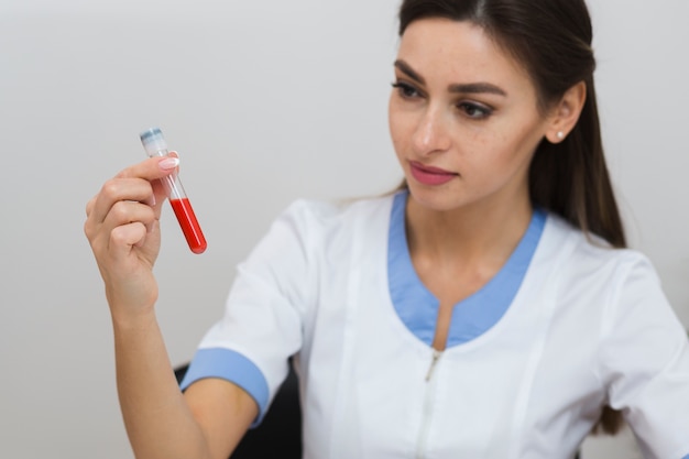 Beau docteur regardant un échantillon de sang