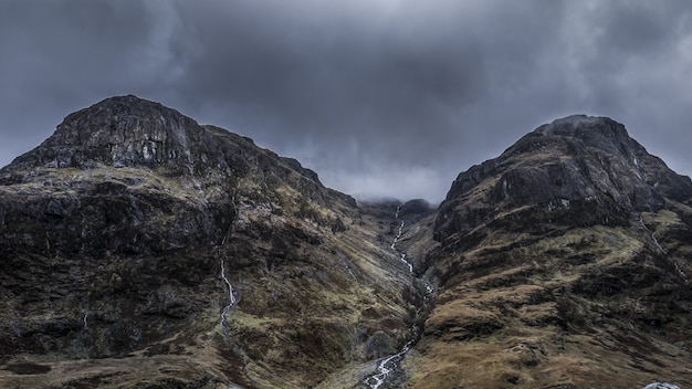 Beau faible angle de vue des hautes montagnes rocheuses sous un ciel d'orage gris pendant la journée