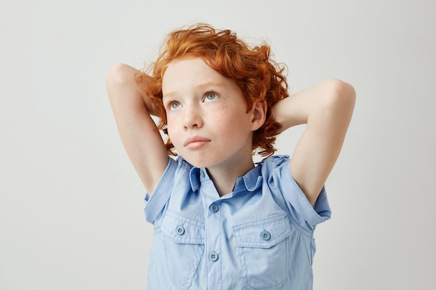 Photo gratuite beau gingembre avec des taches de rousseur croisant les mains derrière la tête, regardant de côté