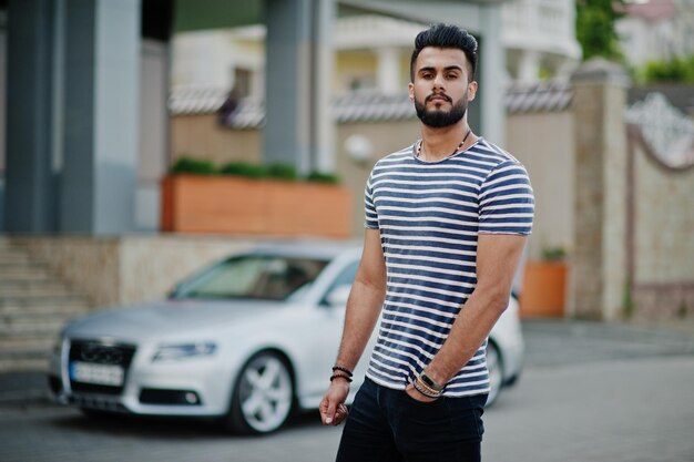 Beau grand homme barbe arabe modèle à chemise dépouillée posé en plein air contre la voiture