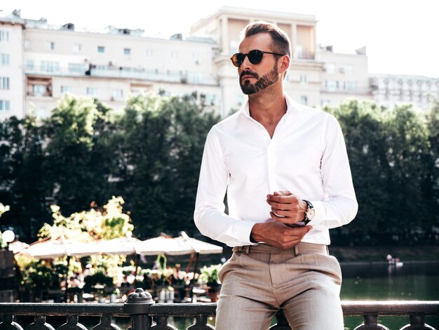 Beau hipster élégant et confiant modèle sexuel sexy homme moderne vêtu d'une chemise blanche et d'un pantalon