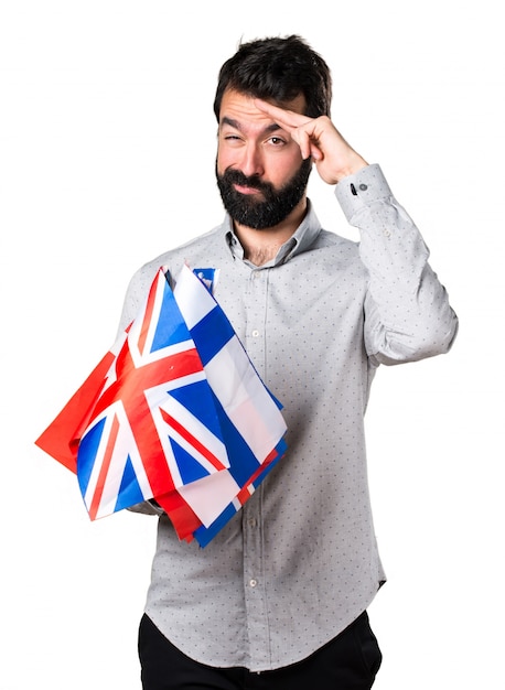 Photo gratuite beau homme à la barbe tenant de nombreux drapeaux et saluant