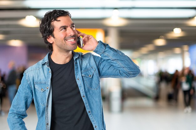 Beau homme parler à mobile sur fond blanc