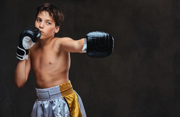 Beau jeune boxeur torse nu pendant les exercices de boxe, concentré sur le processus avec un soin du visage concentré sérieux.