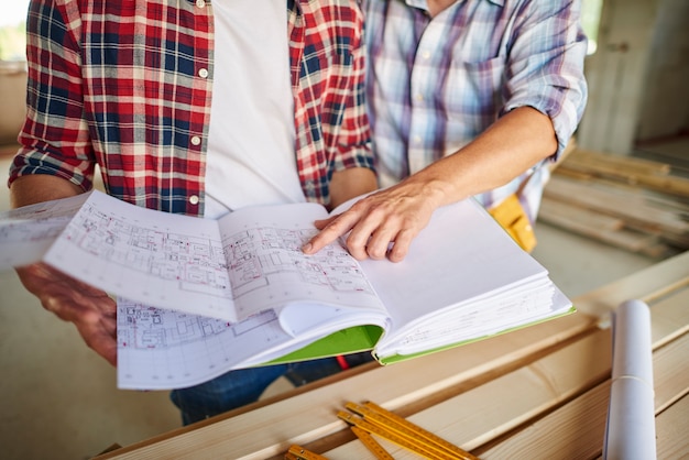 Photo gratuite beau jeune charpentier travaillant avec un homme expérimenté