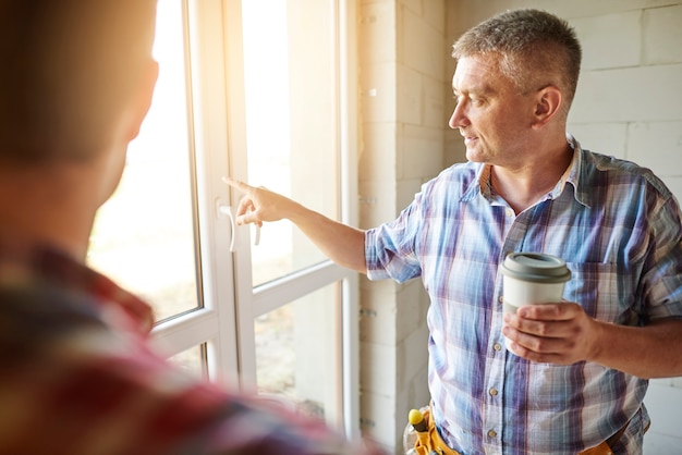 Beau jeune charpentier travaillant avec un homme expérimenté