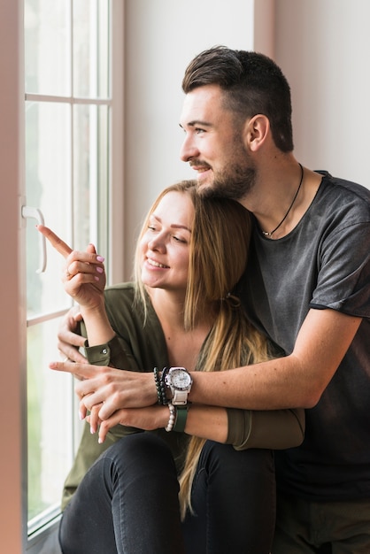 Beau jeune couple assis sur le rebord de la fenêtre à l&#39;extérieur