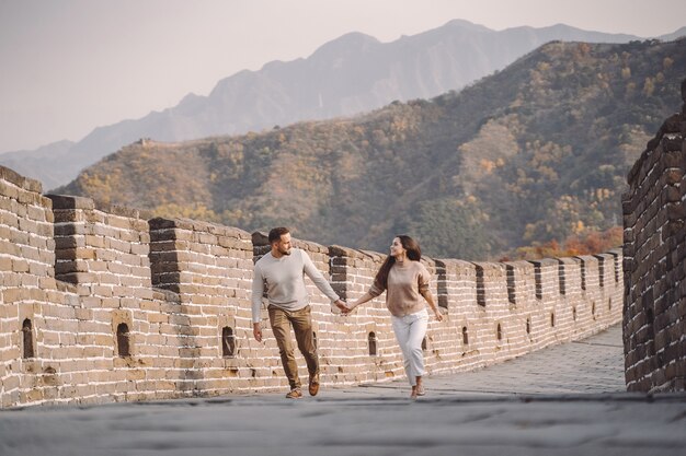 Beau jeune couple courir et sauter à la Grande Muraille de Chine.