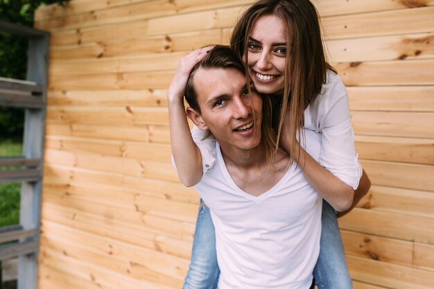 Beau jeune couple posant sur un mur en bois