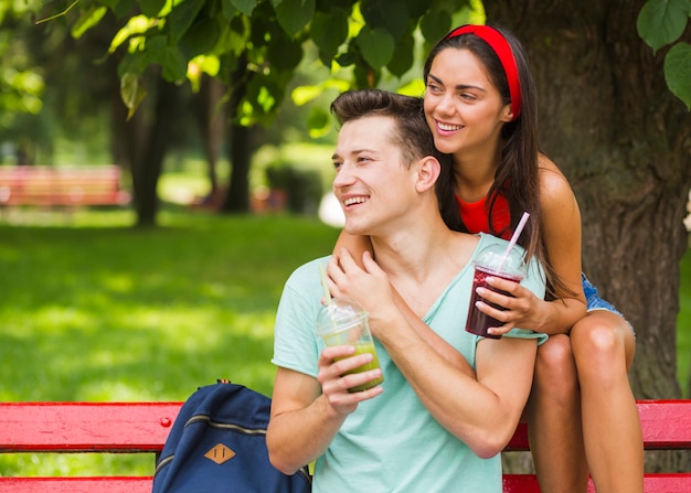 Beau jeune couple tenant des smoothies dans une tasse en plastique à la recherche