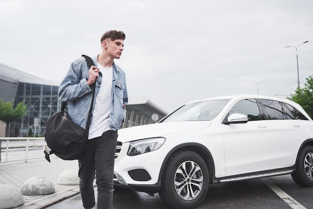 Un beau jeune homme à l'aéroport attend le vol.