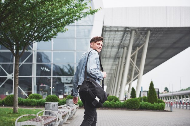 Un beau jeune homme à l'aéroport attend le vol.