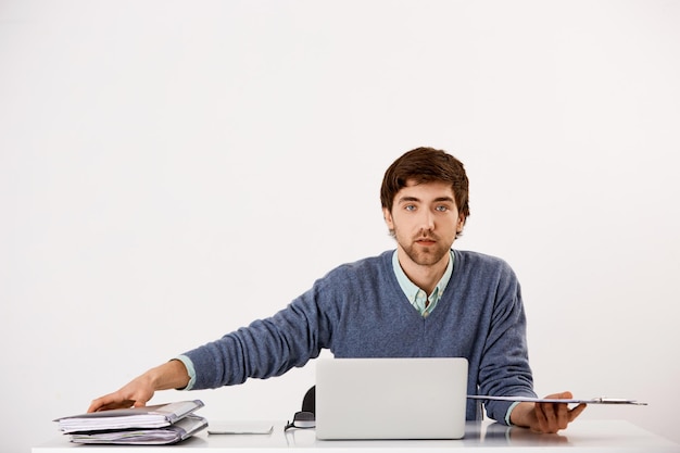 Beau jeune homme d'affaires confiant assis au bureau