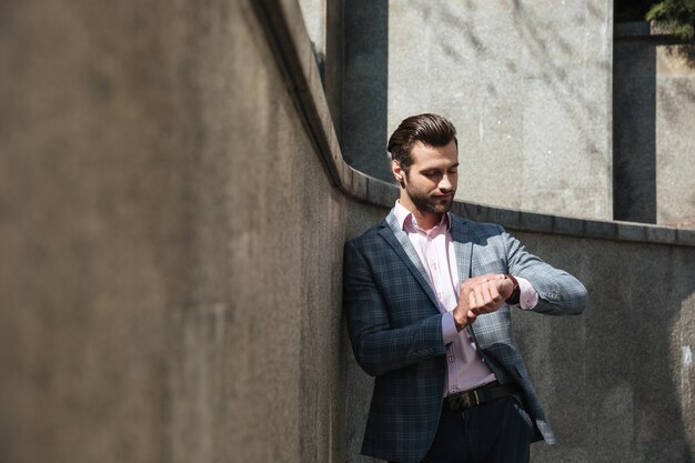 Beau jeune homme d'affaires en regardant la montre.