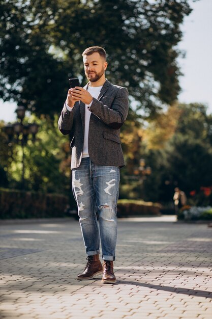 Beau jeune homme d'affaires utilisant un téléphone à l'extérieur de la rue