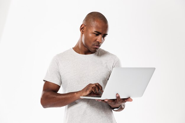 Beau jeune homme africain à l'aide d'un ordinateur portable