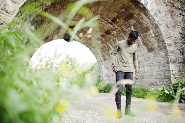 Beau jeune homme afro-américain en vêtements décontractés posant et marchant dans le tunnel