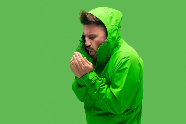 Beau jeune homme barbu de congélation isolé sur une couleur verte à la mode vive au studio.