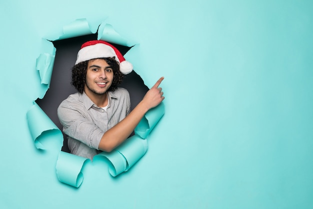 Beau Jeune Homme Bouclé Porter En Bonnet De Noel Côté Pointu Du Trou Sur Du Papier Vert