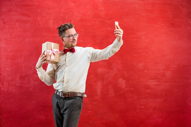 Beau jeune homme avec cadeau et téléphone