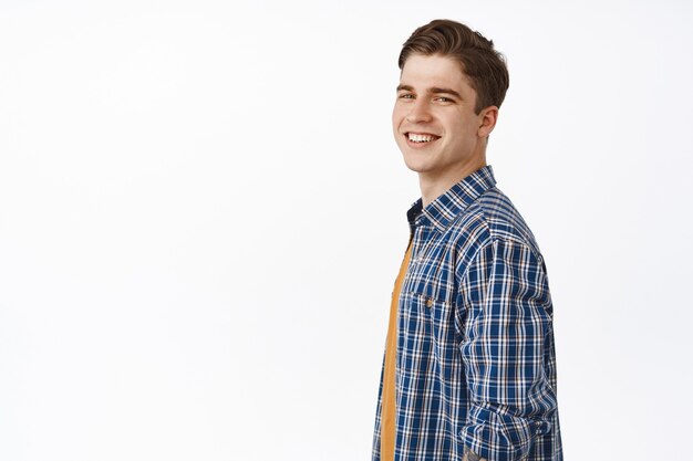 Beau jeune homme caucasien regardant la caméra heureux et insouciant, souriant heureux, debout décontracté en tenue d'été sur blanc