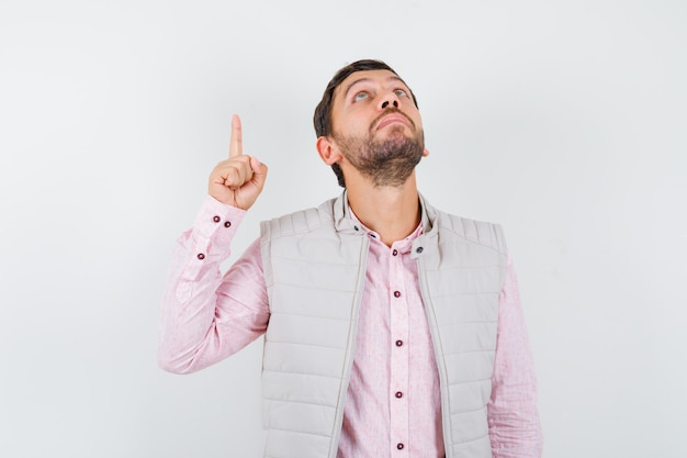 Beau jeune homme en chemise, gilet pointant vers le haut, regardant vers le haut et ayant l'air plein d'espoir, vue de face.