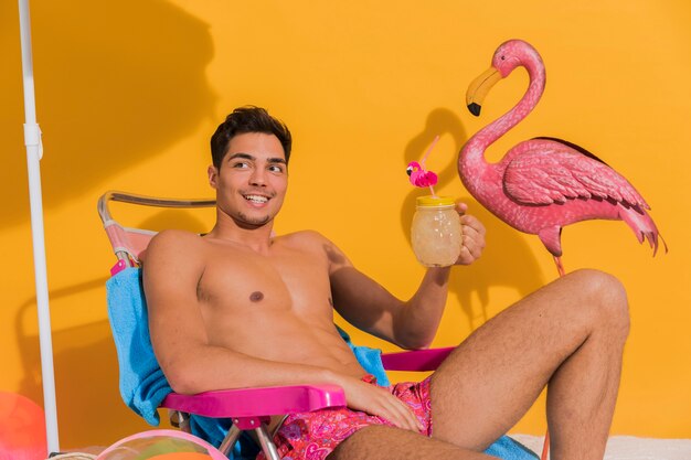 Beau jeune homme avec cocktail sur la plage en studio