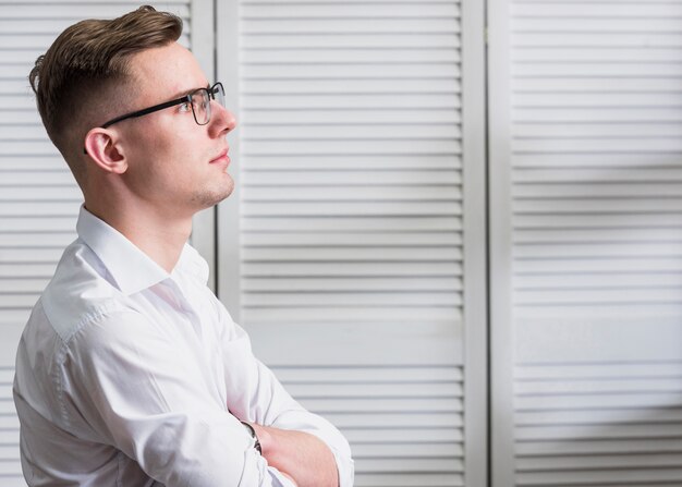 Beau jeune homme contemplé avec des lunettes