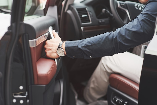 Beau jeune homme en costume complet au volant d'une voiture.