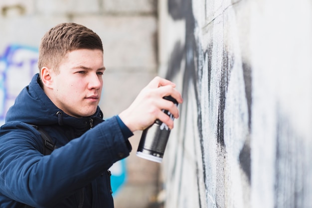 Beau jeune homme dessin graffiti avec un spray