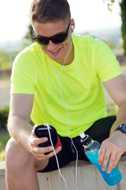 Beau jeune homme écoutant de la musique après la course.