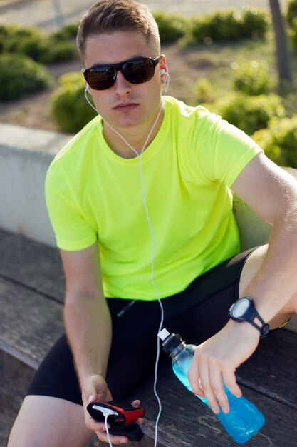 Beau jeune homme écoutant de la musique après la course.