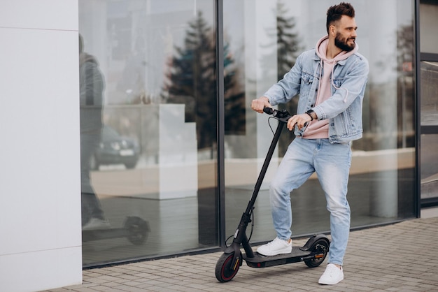 Beau jeune homme faisant du scooter électrique