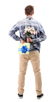 Beau jeune homme avec des fleurs et des cadeaux, isolé sur blanc