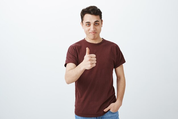 Beau jeune homme montrant son pouce vers le haut. Bien joué!