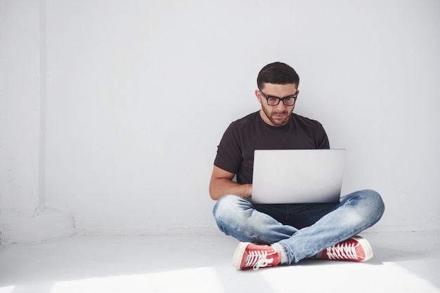 Beau jeune homme avec ordinateur portable et vérifier son emploi du temps sur blanc