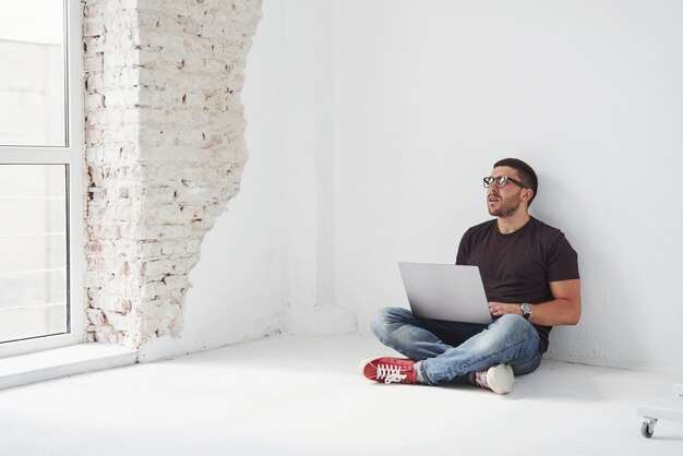 Beau jeune homme avec ordinateur portable et vérifier son emploi du temps sur blanc