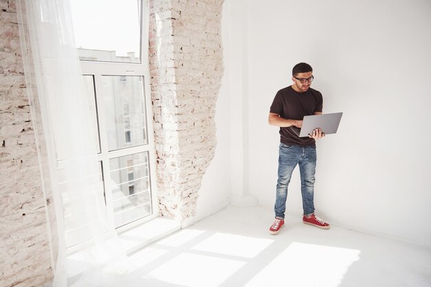 Beau jeune homme avec ordinateur portable et vérifier son emploi du temps sur blanc