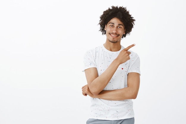 Beau jeune homme à la peau sombre pointant le coin supérieur droit, inviter à l'événement, montrant l'offre promotionnelle