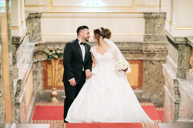 Un beau jeune homme portant un costume noir debout avec sa mariée